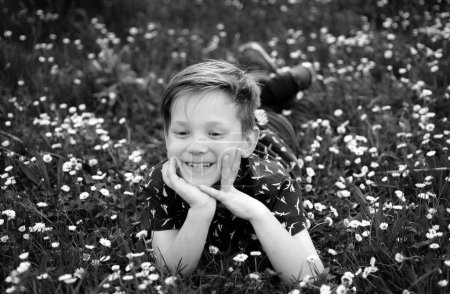 Spring boy on grass. Cute kid on field flower. Dreaming child