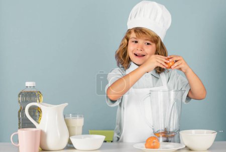 Téléchargez les photos : Enfant chef isolé sur bleu. Drôle petit chef cuisinier enfant portant casquette de cuisinier uniforme et tablier cuisiné dans la cuisine - en image libre de droit