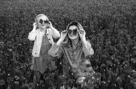Foto de Mamá con una niña en un campo de amapolas rojas disfruta de la naturaleza. Madre e hija en el campo de amapola. Una joven con su hija en un campo de amapola. Feliz maternidad. - Imagen libre de derechos