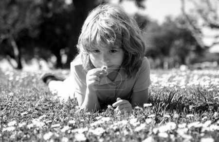 Téléchargez les photos : Cute little girl on the daisy flowers meadow in spring day. Happy childhood. Boy lying on grass. Cute kid child enjoying summer on field. Dreaming kids concept. Environmental and environment - en image libre de droit