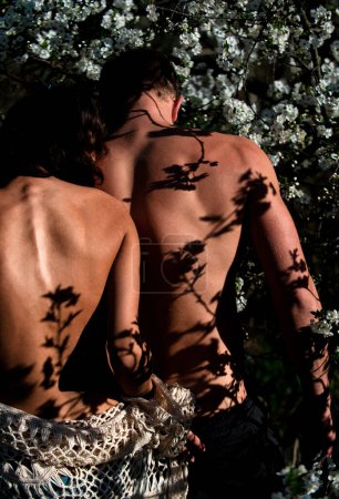 Téléchargez les photos : Couple sensuel en fleur de cerisier. Femme nue homme amoureux en fleurs printemps arbre fleur. Romance, relation, nature, concept d'environnement - en image libre de droit