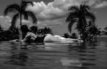 Foto de Mujer sexy relajándose en la piscina infinita mirando a la vista - Imagen libre de derechos