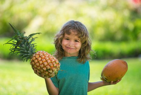 Photo for Child boy holding pineapple and coconut smiling with happy face. Summer fruits - Royalty Free Image