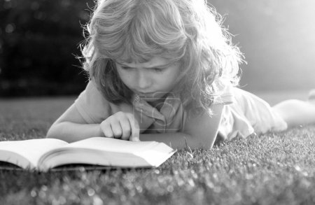 Téléchargez les photos : Mignon garçon enfant avec des livres à l'extérieur. Camp d'été. Concept d'apprentissage et d'éducation des enfants - en image libre de droit