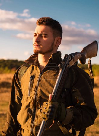 Close up Portrait of hamdsome Hunter. Hunter with shotgun gun on hunt. Hunter aiming rifle in forest. Hunter man