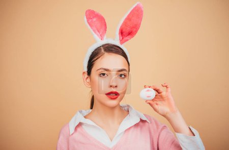 Feliz Pascua. Lápiz labial beso huella en huevo de Pascua. Conejita de Pascua mujer, conejo y niña. Retrato de una mujer feliz con orejas de conejo. Caza de huevos
