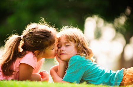 Téléchargez les photos : Charmant amour. Petite fille embrassant garçon à l'extérieur dans le parc. Relations enfants - en image libre de droit