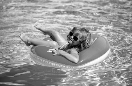 Téléchargez les photos : Vacances d'été. Week-end d'été pour enfants. Garçon dans la piscine. Garçon drôle sur le cercle en caoutchouc gonflable - en image libre de droit