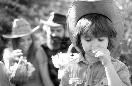 Photo for Family doing picnic in garden. Young smiling kid leisure together sunny day. Boy sniff flower - Royalty Free Image