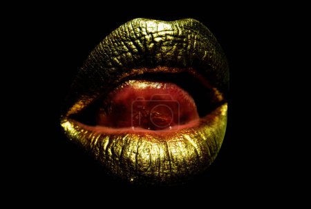 Foto de Hermosa boca de oro de mujer con labios. Labios dorados sensuales, labios sexys. Mujer lengua lamiendo sexy labios - Imagen libre de derechos