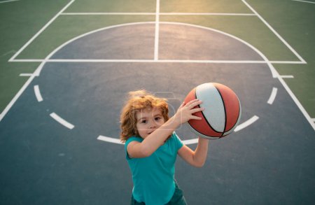 Téléchargez les photos : Un gamin qui joue au basket avec une balle. Mode de vie actif des enfants - en image libre de droit