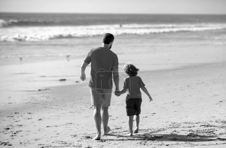 Photo for Dad and child having fun outdoors. Childhood and parenting concept. Father and son walking on summer beach - Royalty Free Image