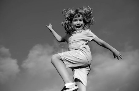 Foto de Divertido niño feliz divirtiéndose en el parque en el cielo azul. Niño disfrutar de la naturaleza, concepto de la infancia - Imagen libre de derechos
