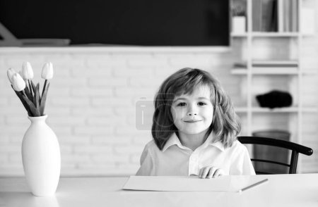 Foto de Una sonriente educación escolar. Alumno de primaria en el interior. Después de la escuela. El chico se prepara para la escuela - Imagen libre de derechos