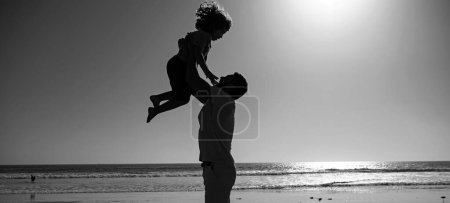 Photo for Father throws son up against the blue sky. Handsome man father carrying young boy son. Happy dad holding child. Dad throwing child. Happy family concept - Royalty Free Image