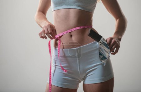 Woman with measuring tape. Weight loss concept. Slim girl with centimeter. Closeup woman measuring her waist with tape.