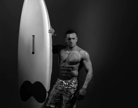 Surfbrettmann mit Leibeigenschaft. Surfer mit Surfbrett. Sexy Mann nass am ganzen Körper hält Leibeigenenbrett mit der rechten Hand, zeigen fit und muskulösen Körper, Modell posiert