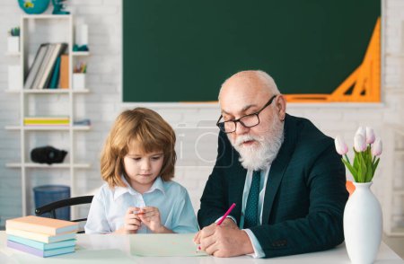 Photo for Mature grandfather helping to grandson with school assignment, older teacher training pupil in lesson at home, homeschooling concept - Royalty Free Image