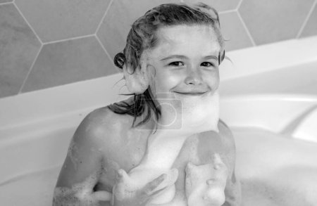 Niedliches Kind waschen und baden in einer Badewanne mit Schaum. Lustiges Kindergesicht in der Badewanne gebadet