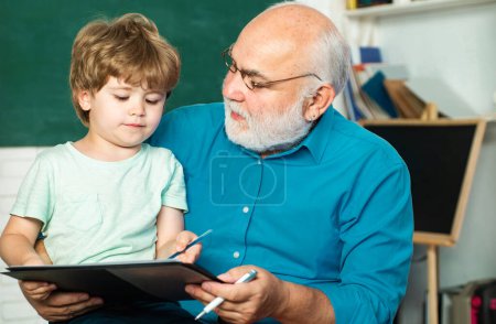 Photo for Grandfather talking to grandson. Family generation and relations concept. Happy cute clever boy and old tutor with book. Funny little child having fun on blackboard background - Royalty Free Image