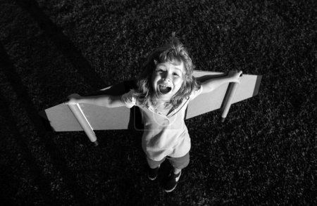 Téléchargez les photos : Enfant excité avec des ailes de sac à dos. Enfant jouant pilote aviateur et rêve à l'extérieur dans le parc. Enfant souriant rêvant de vacances d'été et de voyages. Garçon rêve de voler. Enfant insouciant jouant à l'extérieur - en image libre de droit