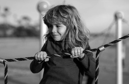 Foto de Niño lindo niño divertido mientras juega en el patio de recreo. Verano, infancia, ocio y concepto infantil - Imagen libre de derechos