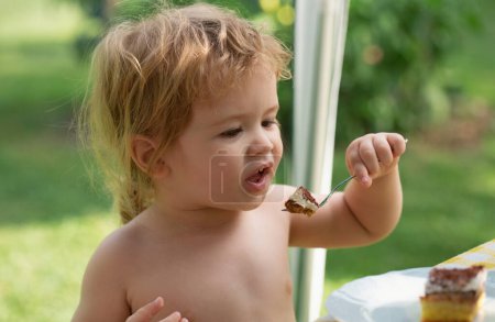 Foto de Bebé comiendo pastel. Pequeño niño comiendo pastel durante la fiesta de aplastamiento de pastel - Imagen libre de derechos