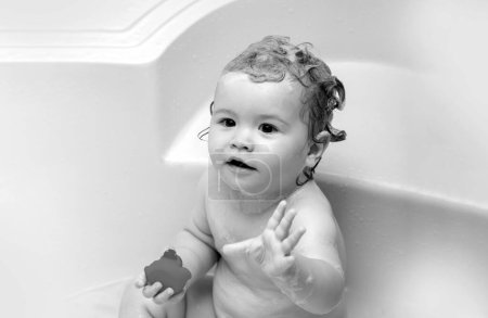 Foto de Niño encantador jugando con espuma. Feliz bebé tomando un baño jugando con burbujas de espuma. Un niño pequeño en una bañera. Niño sonriente en el baño con pato de juguete. Lavado y baño infantil. Cuidado e higiene de los niños - Imagen libre de derechos