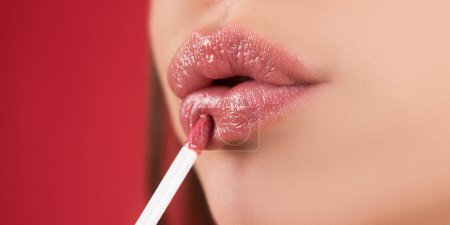 Photo for Closeup painting lips with bright lipstick. Female lipgloss. Beauty young woman Lips - Royalty Free Image