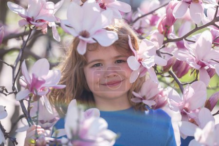 Spring fun for kids. Child play outdoors in a beautiful spring garden. Kid face in flowers. Adorable little kid in blooming cherry garden on beautiful spring day. Happy child during spring blossom