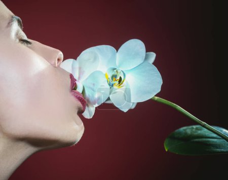 Téléchargez les photos : Orchidée et lèvres de femme. Orchidée fleur sur sensuelle femme bouche - en image libre de droit
