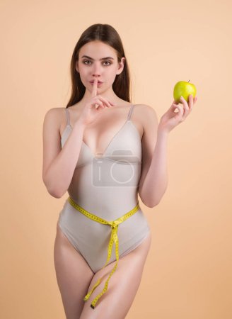 Photo for Secret diet. Young woman measuring waist. Weight loss diet. Slim waist, apple and measuring tape. Weight loss and dieting. Diet for waistline. Fit Body. Dieting for Waist and belly. Healthy diet - Royalty Free Image