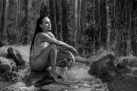Téléchargez les photos : Femme humide et sexy se baigne dans une belle cascade. Summer beauté sexy femme portrait en plein air. belle jeune femme sexy en bikini sous les éclaboussures de l'eau de la cascade - en image libre de droit