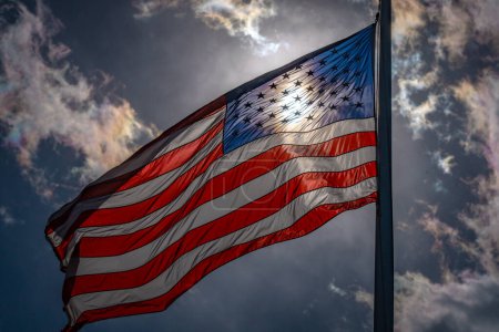 Téléchargez les photos : Concept d'élection et de vote américain. Drapeau américain. Un drapeau américain sur un ciel sombre et dramatique. Drapeau des États-Unis agitant près du soleil - en image libre de droit