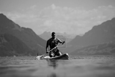 Photo for Man with paddle board. Man paddling on paddleboard. Muscular strong Hispanic man on sup board paddle surfing. SUP surfing in summer vacation in lake. Strong muscular wet body. Bare naked torso - Royalty Free Image