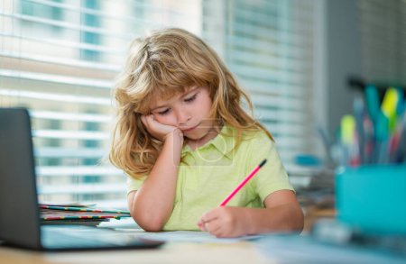 Photo for Tired schoolboy while doing homework. Child writing homework in school class. Funny child girl doing homework writing and reading at home. Little student at desk in school classroom - Royalty Free Image