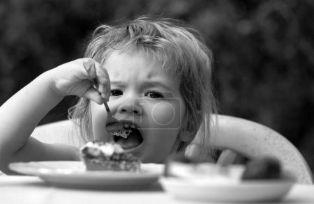 Baby eating cake. Child eat cupcake outdoors