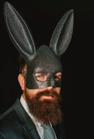 Photo for Bearded hipster in suit is ready for carnival. Funny bearded man in carnival rabbit mask. Handsome man in carnival mask ballroom rabbit with long ears sensual on a black background - Royalty Free Image