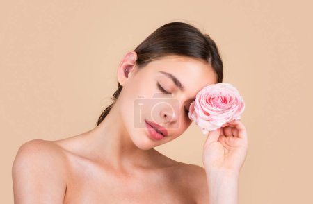 Téléchargez les photos : Beauté visage femme spa avec maquillage naturel et fleurs roses, modèle beauté fraîche jeune spa. Beaux cosmétiques de bien-être féminin. Spa et bien-être, concept de soins de la peau. Traitement du visage - en image libre de droit