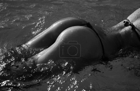 Téléchargez les photos : Sexy curves girl butt in bikini in pool. Sexy buttocks. Young woman shows a beautiful ass buttocks in water. Summer background - en image libre de droit