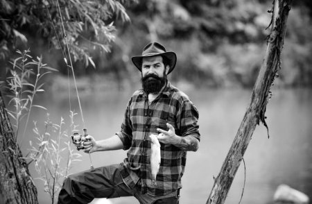 Téléchargez les photos : Portrait de pêcheur pêchant sur un rever. Pêcheur détendu homme avec une canne à pêche un jour d'été - en image libre de droit