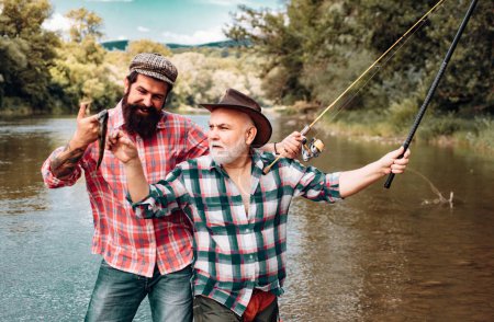 Téléchargez les photos : Pêcheurs amis et truites trophées. Pêche père et fils. Générations hommes pêchant dans la rivière - en image libre de droit