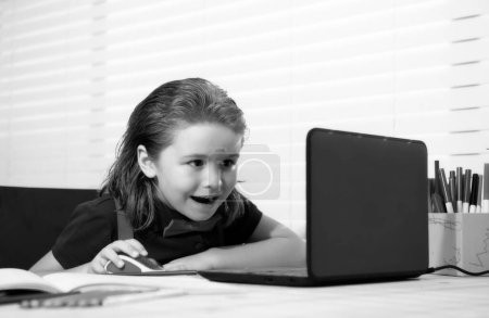 Photo for School boy with a happy smiling face studying and using computer laptop and writing on notebook. Nerd funny pupil - Royalty Free Image