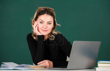 Photo for Portrait of teacher or female tutor working at table in college or school. Young women student studying in class - Royalty Free Image
