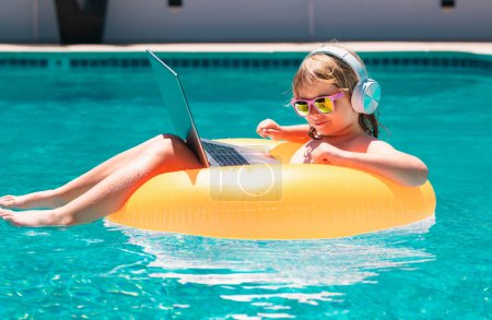 Photo for Kids working with laptop on summer vacation holidays. Little freelancer using computer, remote working in swimming pool. Summer travel and business concept - Royalty Free Image