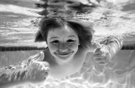 Foto de Child swim under water in sea. Kid swimming in pool underwater. Happy boy swims in sea underwater. Children in water - Imagen libre de derechos
