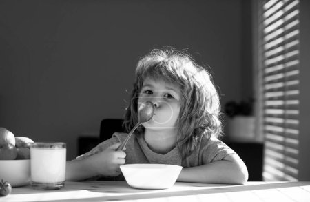 Téléchargez les photos : Un gamin drôle avec une assiette de soupe. Dîner enfant - en image libre de droit