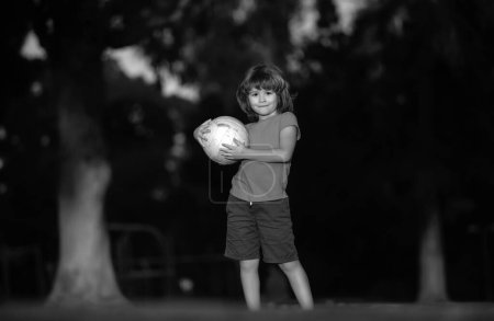 Little kid boy playing football in the field with soccer ball. Concept of children sport. Active ball games
