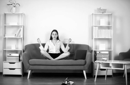 Femme d'affaires entrepreneure faisant de l'exercice de yoga sur le canapé sur le lieu de travail au bureau. Employé sentir équilibre harmonie relaxation. calme comptable fille méditation dans bureau