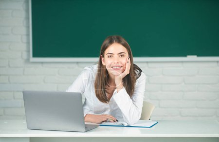 Photo for Cute teen girl, school student write notes, watch video online webinar, learn on laptop, sit in classroom, distance elearning course, video conference on pc. - Royalty Free Image